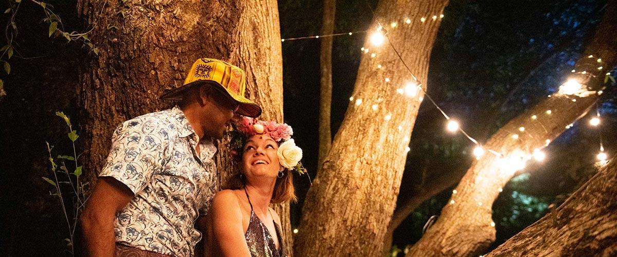 A couple sitting in a tree with light bulb string lights during a previous instalment of Jungle Love Festival