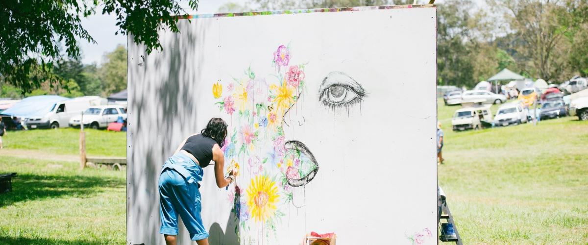 Artist painting a mural at Jungle Love Festival