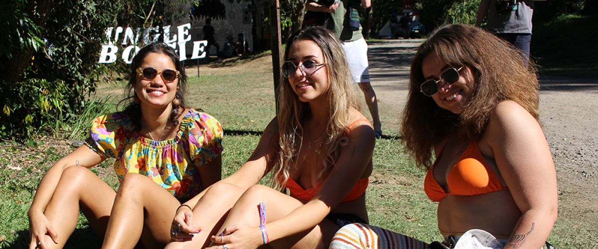 Three girls sitting in the sun with a drink in a cup