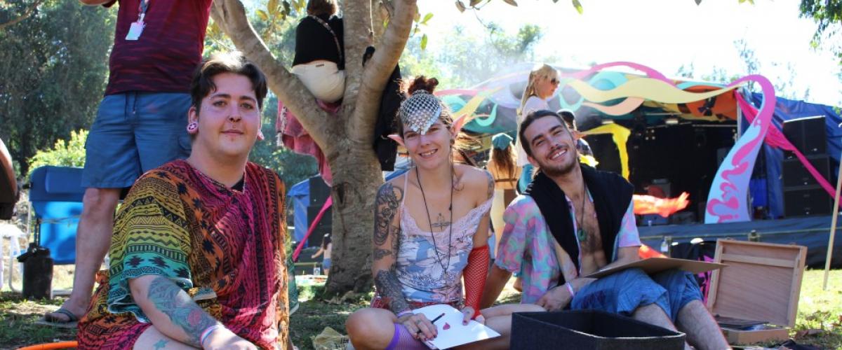 Festival goers chilling under a tree and smiling